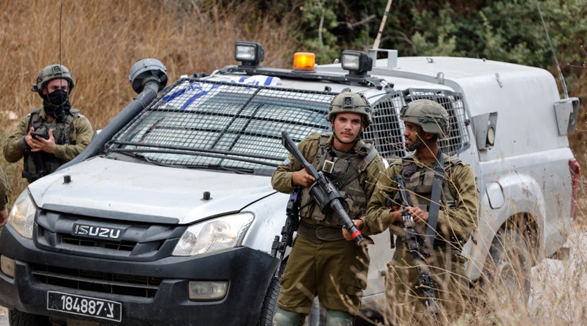 Israeli soldiers stand near the scene where, according to the IDF, a Palestinian had thrown a grenade and shot at soldiers who returned fire at him, near Neve Tzuf, in the West Bank