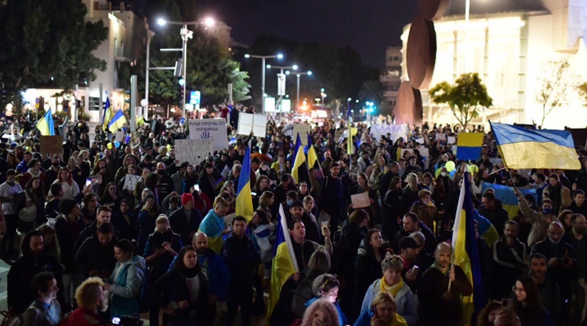 Demonstrators carry placards and flags during a protest march against the Russian invasion of Ukraine, in Tel Aviv