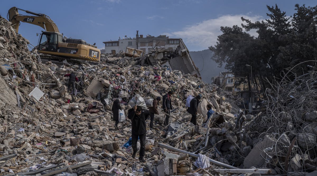People walk through the rubble of destroyed buildings in Antakya, southeastern Turkey