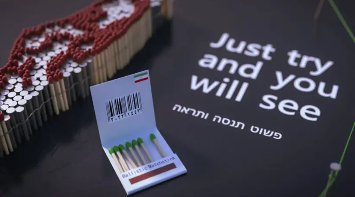 Israel composed of nails and matches and a book of matches next to words in Hebrew and English declaring: “Just try and you will see.”