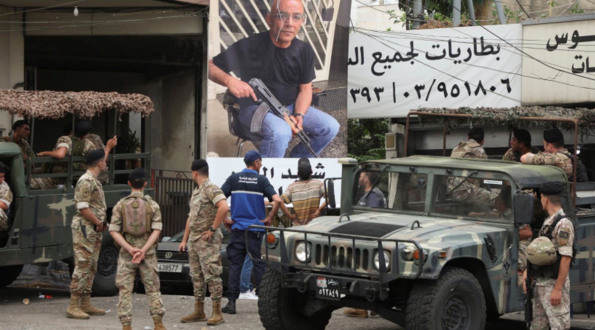 Lebanese army members stand near a poster of Fadi Bejjani