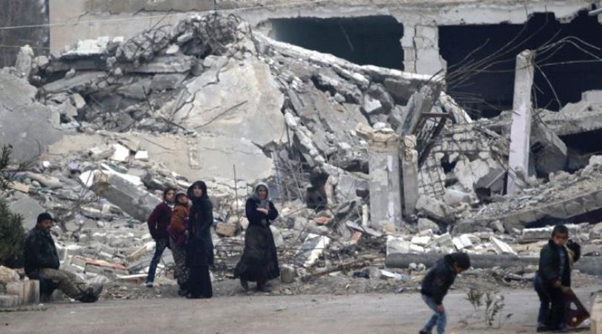 People stand near rubble of damaged buildings in the northern Aleppo countryside in Syria