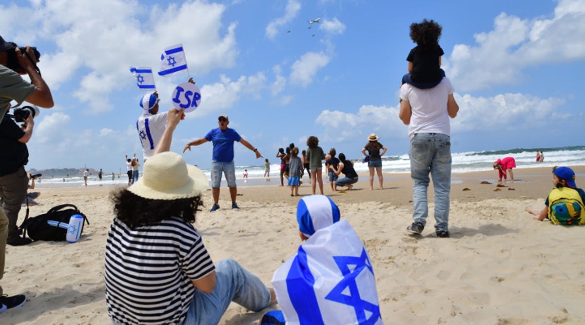 People on the beach in Tel Aviv watch the military airshow on Israel's 74th Independence day