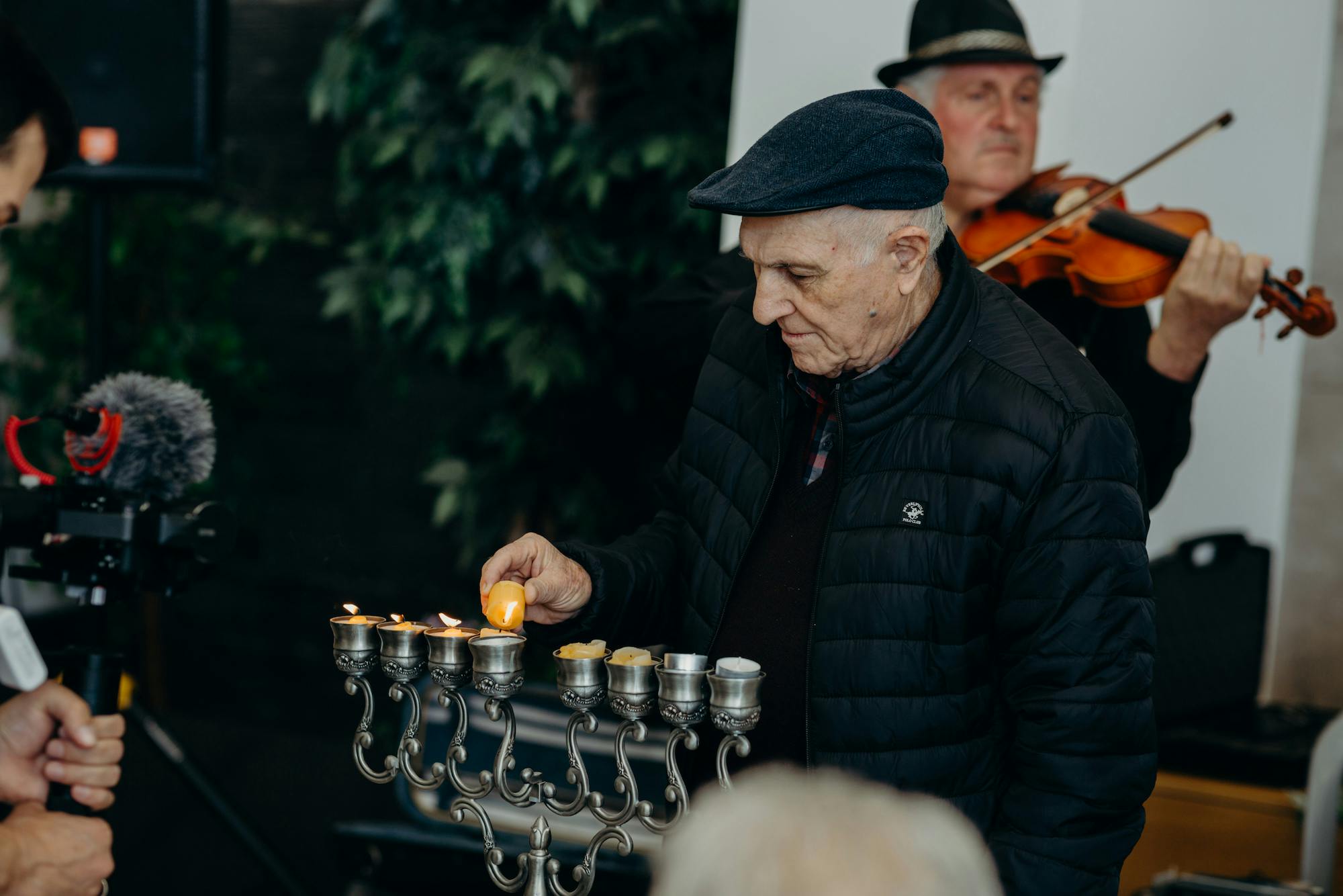 An elderly man lighting up a Hanukkiah