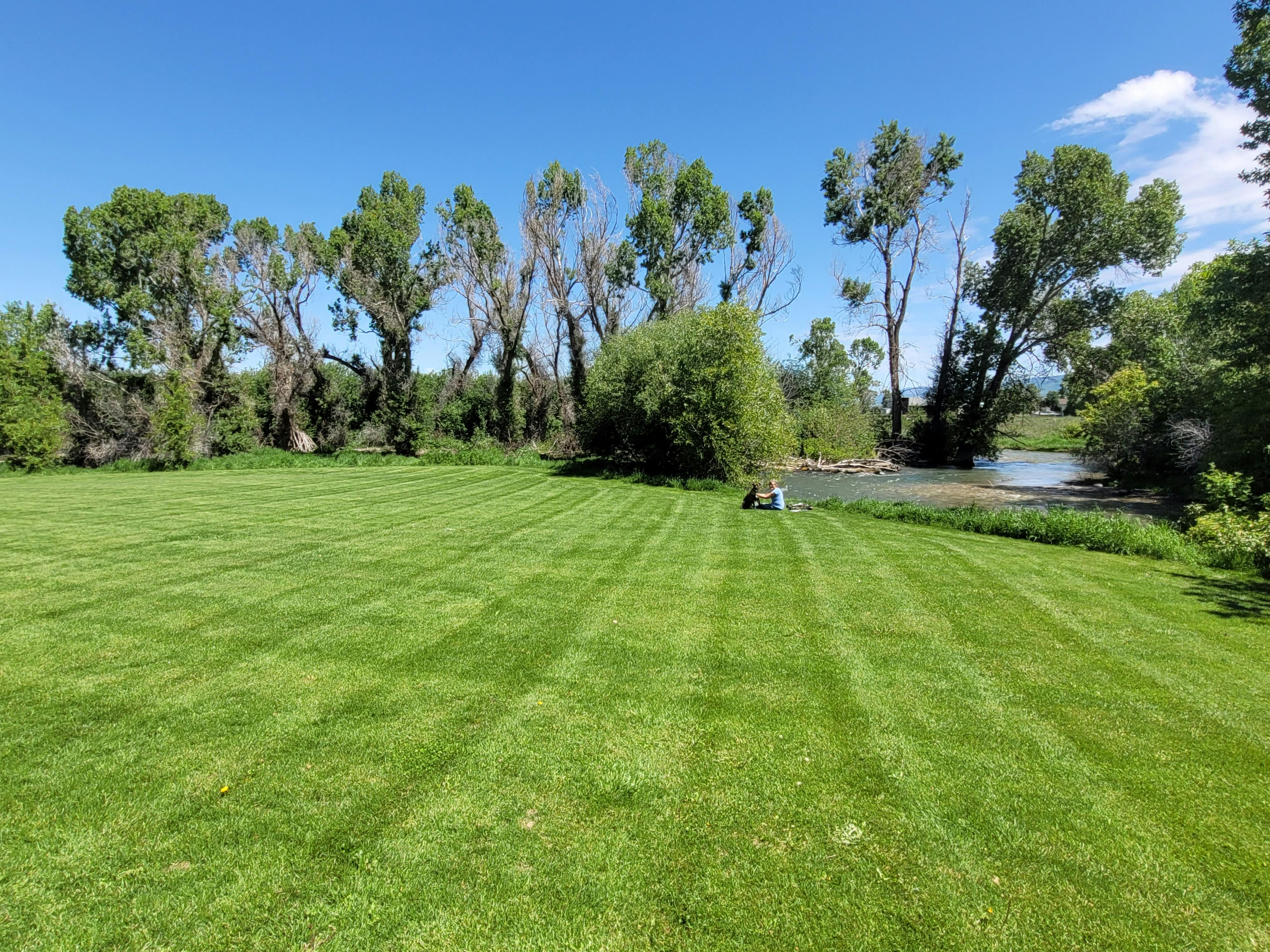 Lots of green grass and a stream running beside Brookside Park in Victor Idaho. 