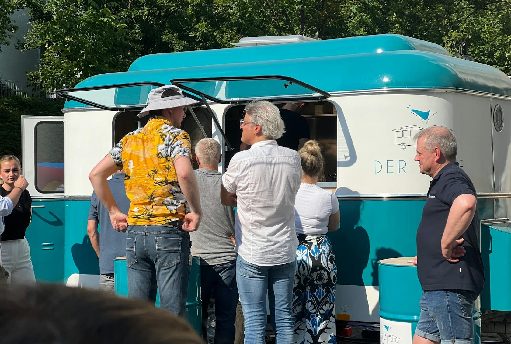 A group of people in front of a food truck in the sun.