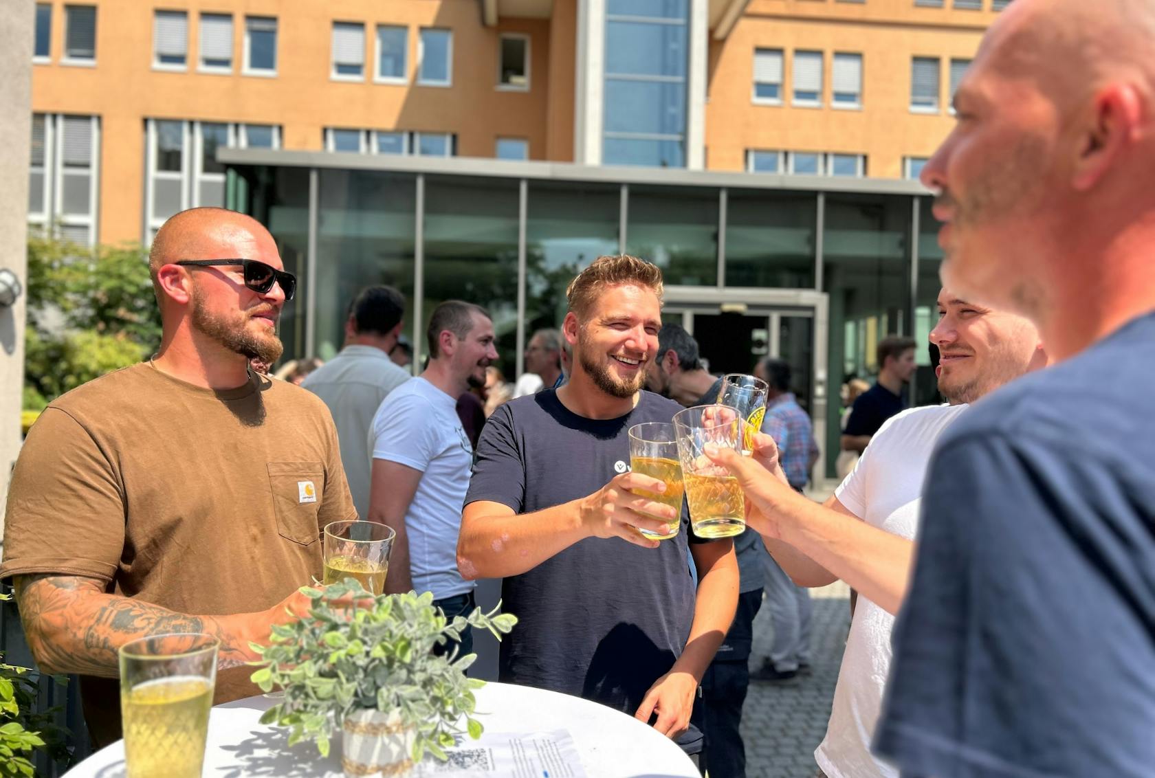 A group of four men laugh and toast each other.