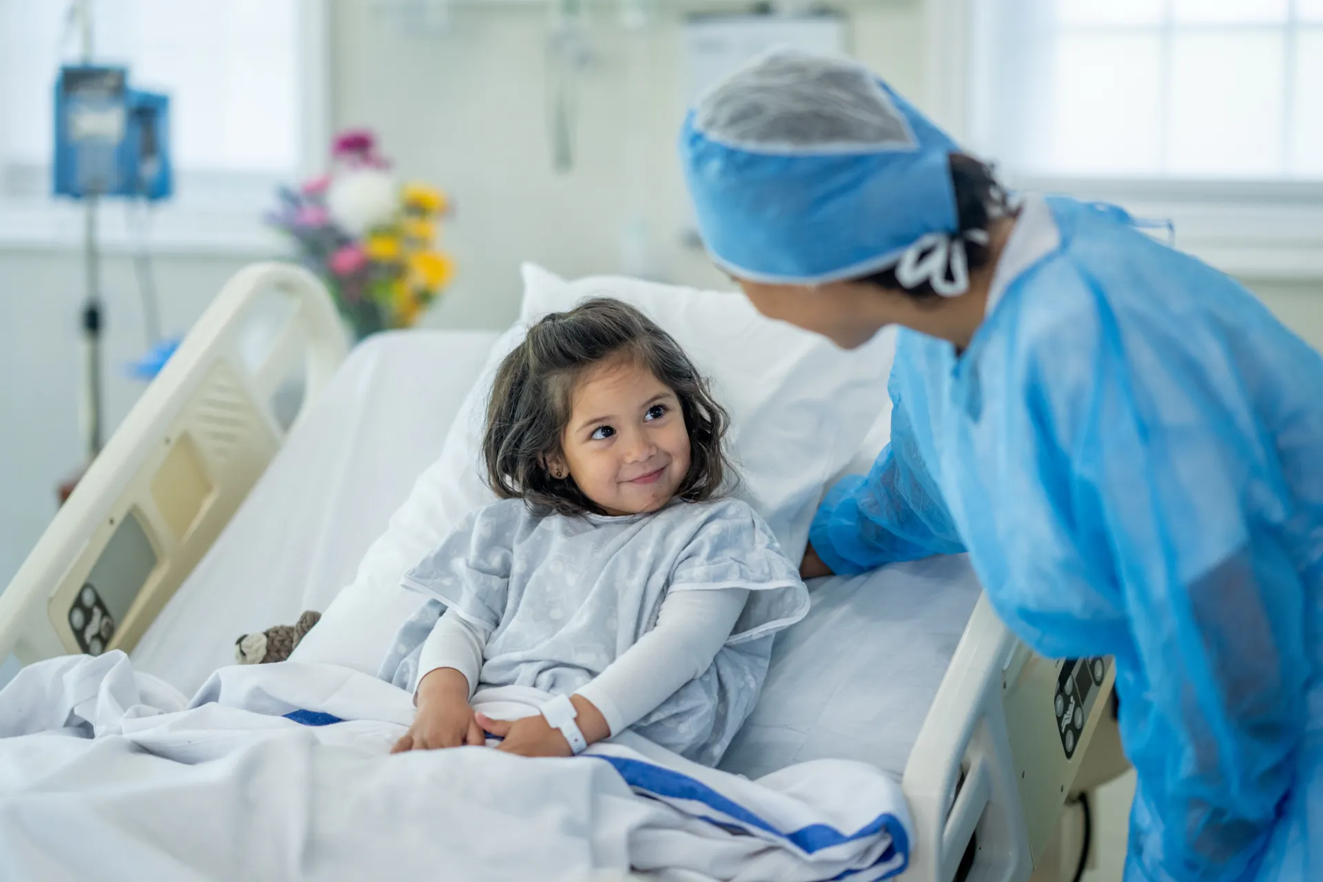 A child in a hospital bed smiling at a clinician