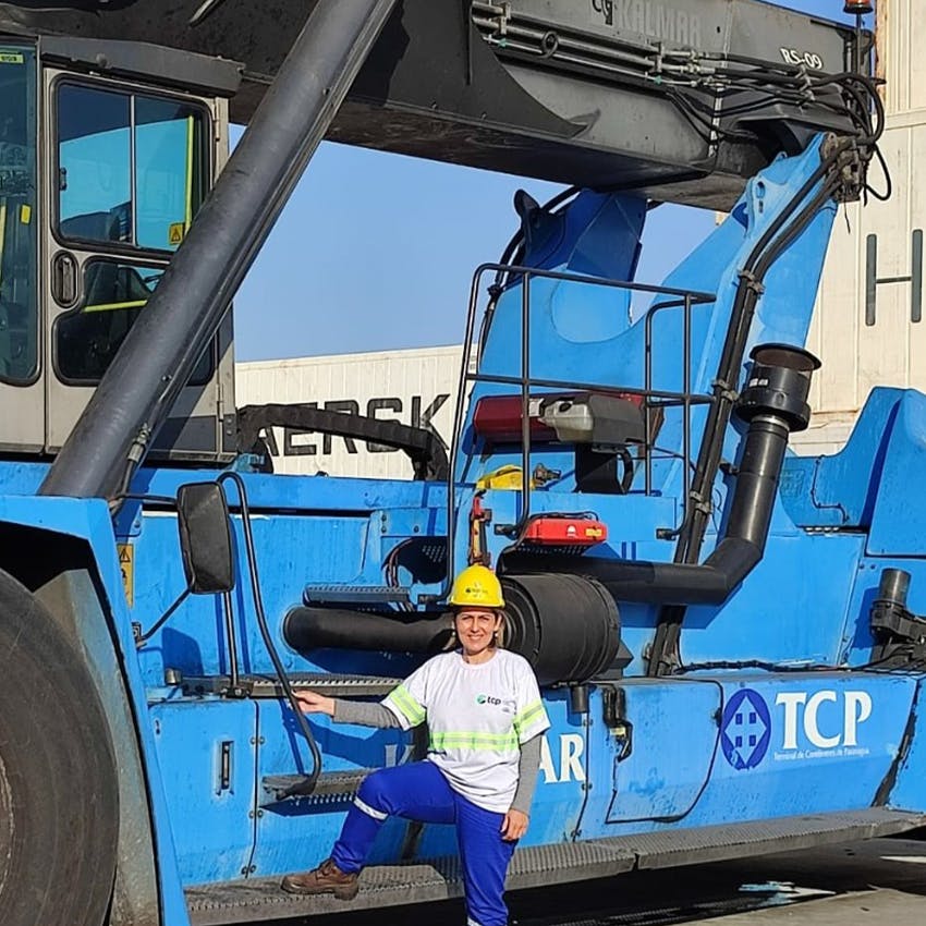 Andreia next to one of the reach stackers she operates at the port terminal in Paranaguá, PR. 2021.