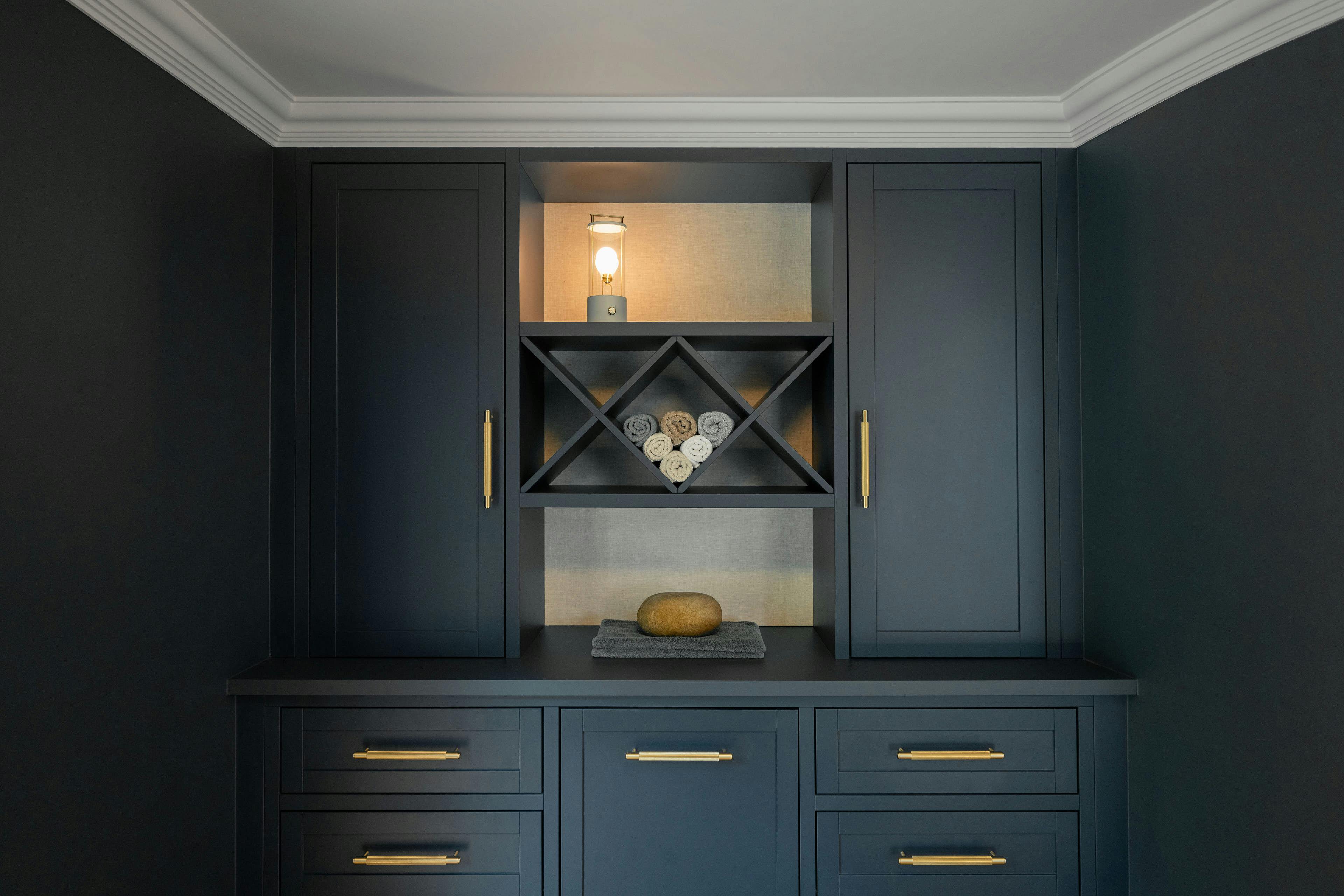 Gestaltung eines Home-Gyms und Fitnessraums. Im Bild ein eleganter, subtil beleuchteter Einbauschrank mit Handtüchern.