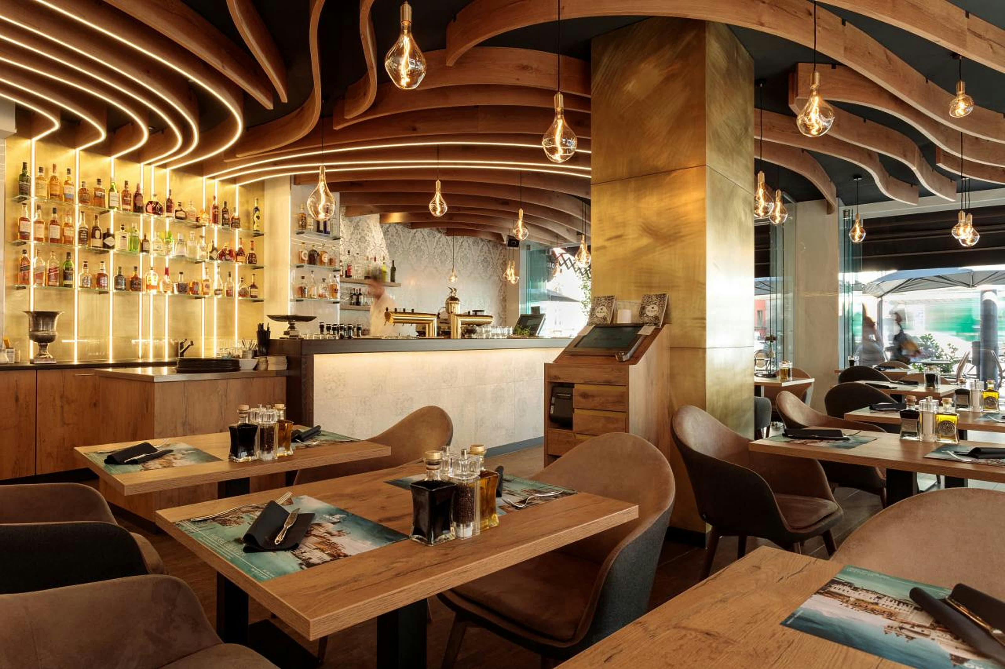 Eine modern-designte Pizzeria mit vergoldeten Säulen und handgefertigten Deckenpanelen