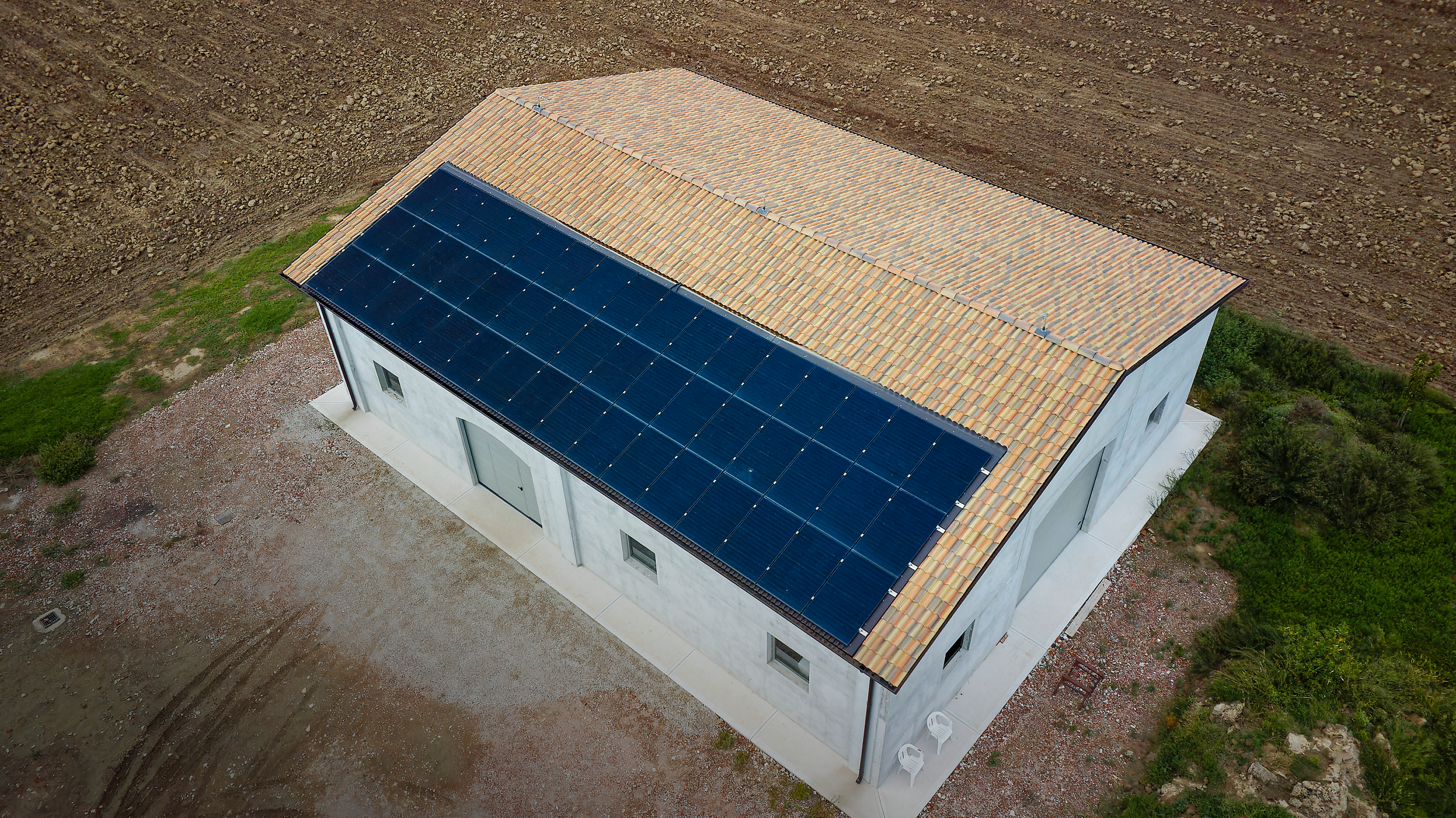 A colpo d’occhio sembra un impianto unico, ma la stringatura e la divisione dei sistemi lo rendono di fatto un progetto gemello, con due impianti indipendenti. Si tratta di un capannone situato a Mortizzuolo, una ricostruzione da terremoto curata da SEC Costruzioni che ora fornisce energia rinnovabile a due abitazioni.