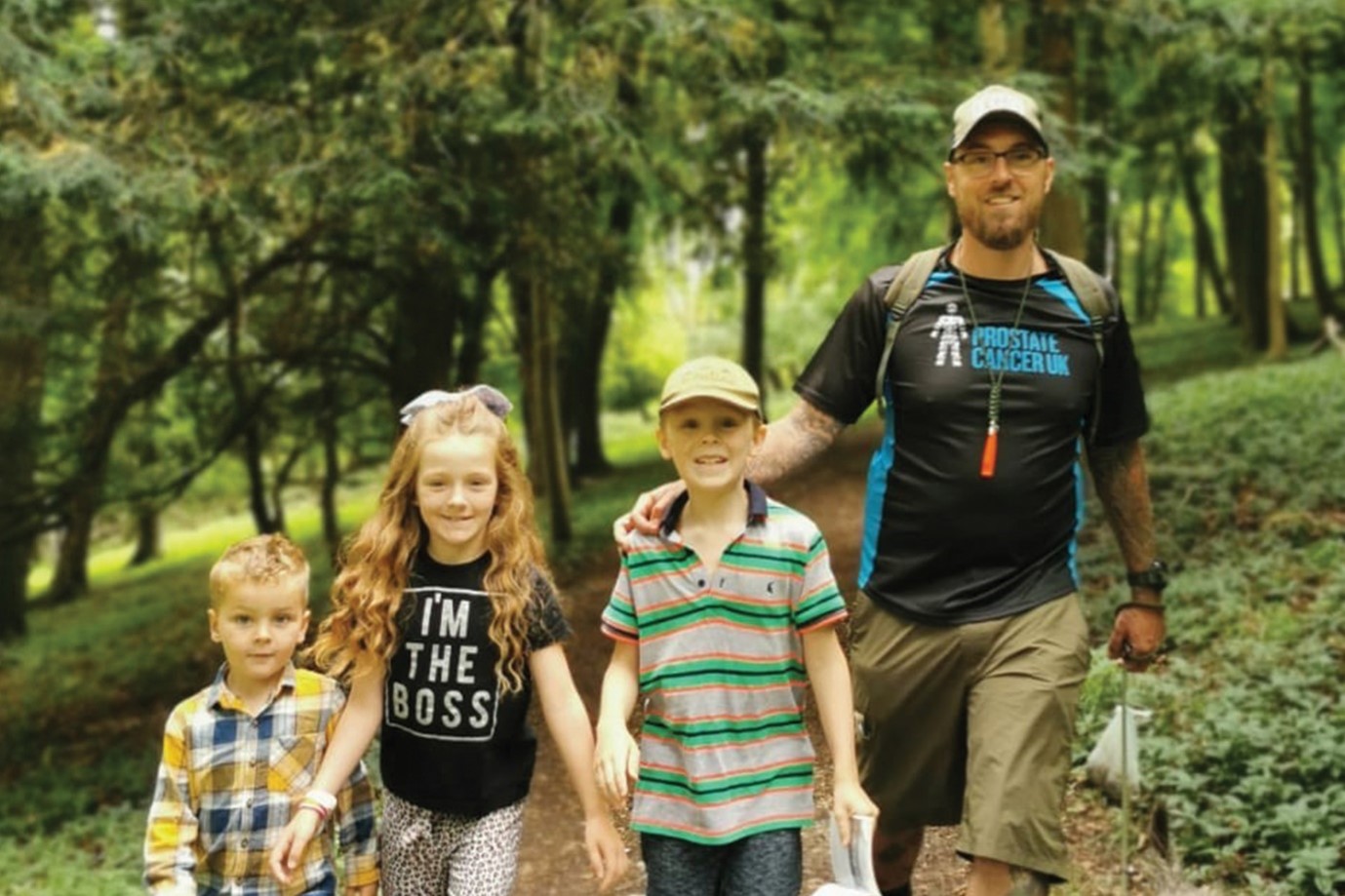 Image of a man in a Prostate Cancer UK t-shirt with three children, walking outside