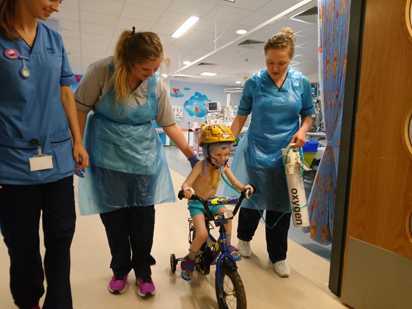 Nurses helping a young child to ride their bike in a hospital