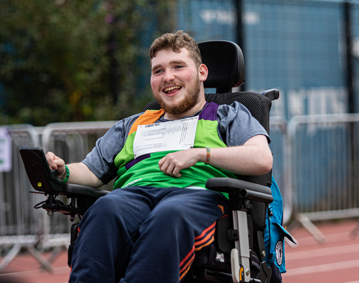 Man, smiling in wheelchair on a athletic track