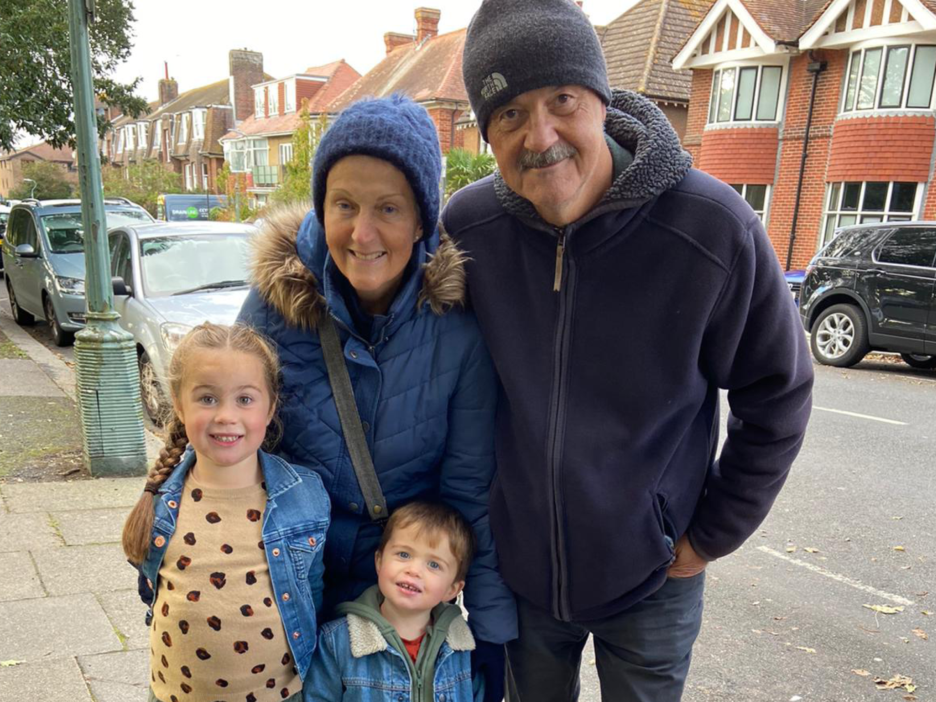 A family of man, woman and two children standing in the street