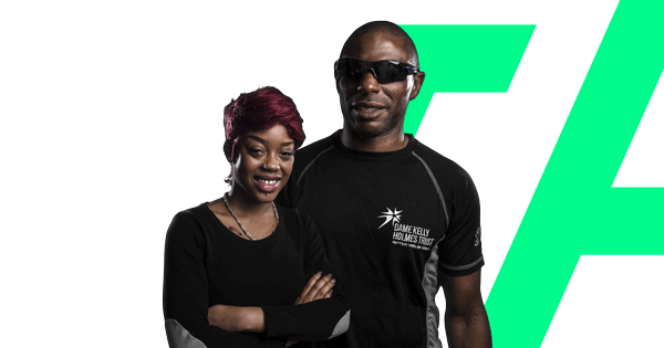 Two people in The Dame Kelly Holmes Trust tops smiling towards the camera on a transparent background.