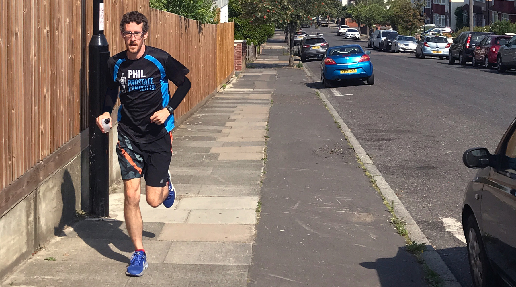 Man running along the street in a Prostate Cancer UK running top