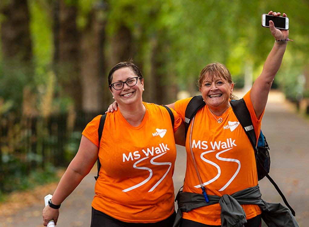 Two women wearing orange t-shirts walking.