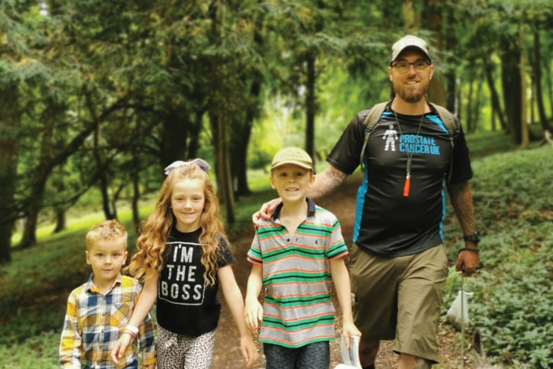 A man and three children walking through the woods.