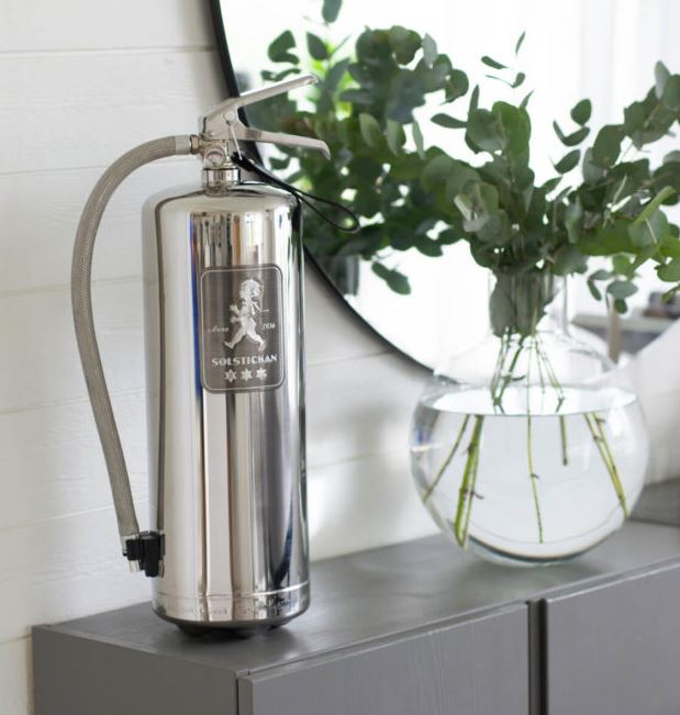 Silfur slökkvitæki á grárri hillu.