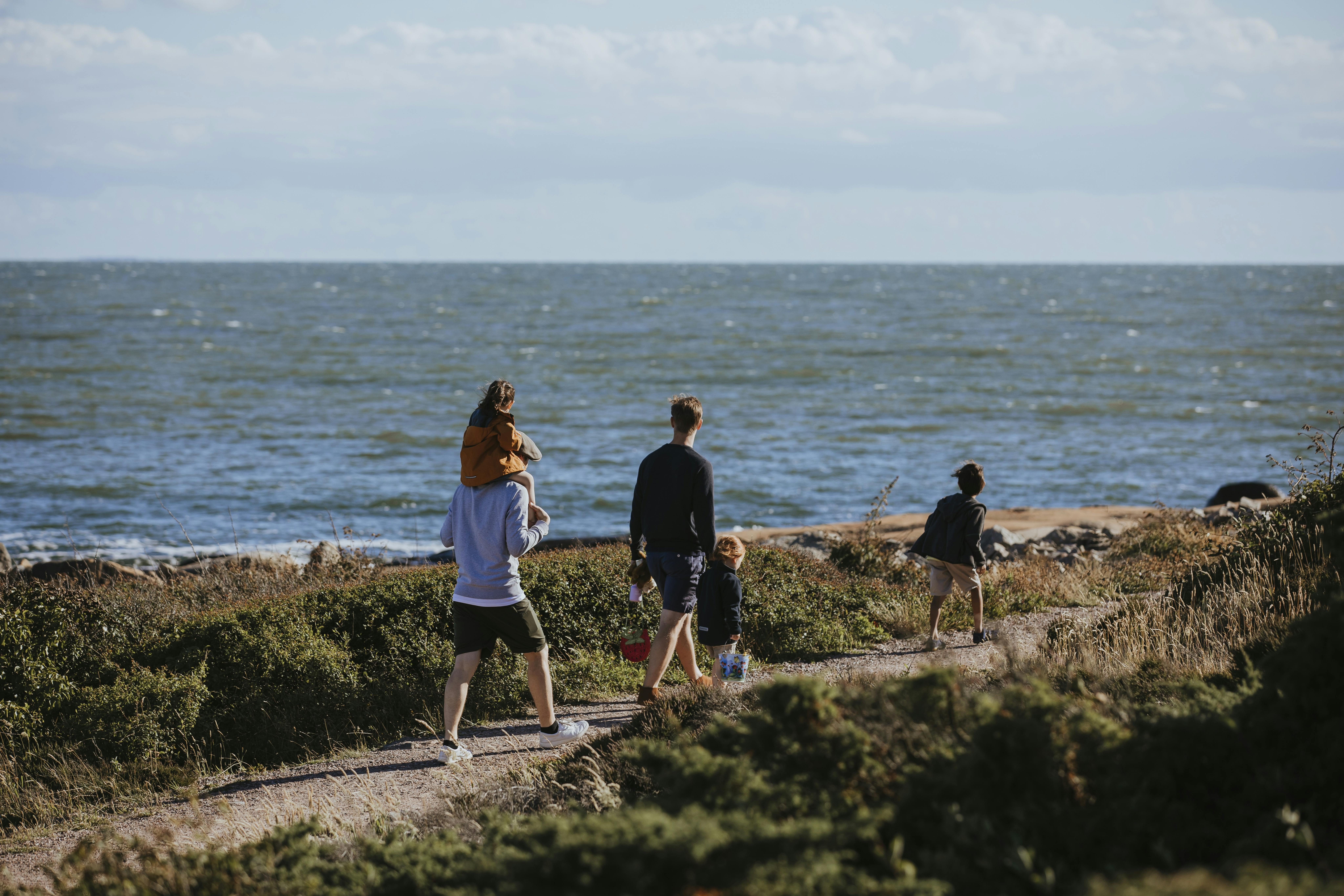 Familie spaziert am Prinz Bertil Wanderweg entlang des Meeres.