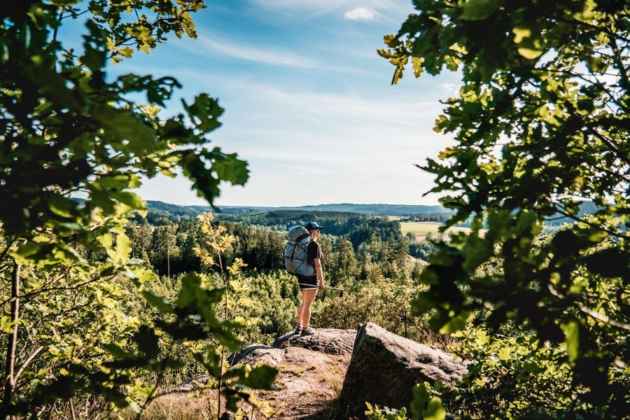Person står på en klippa och blickar ut över naturen.