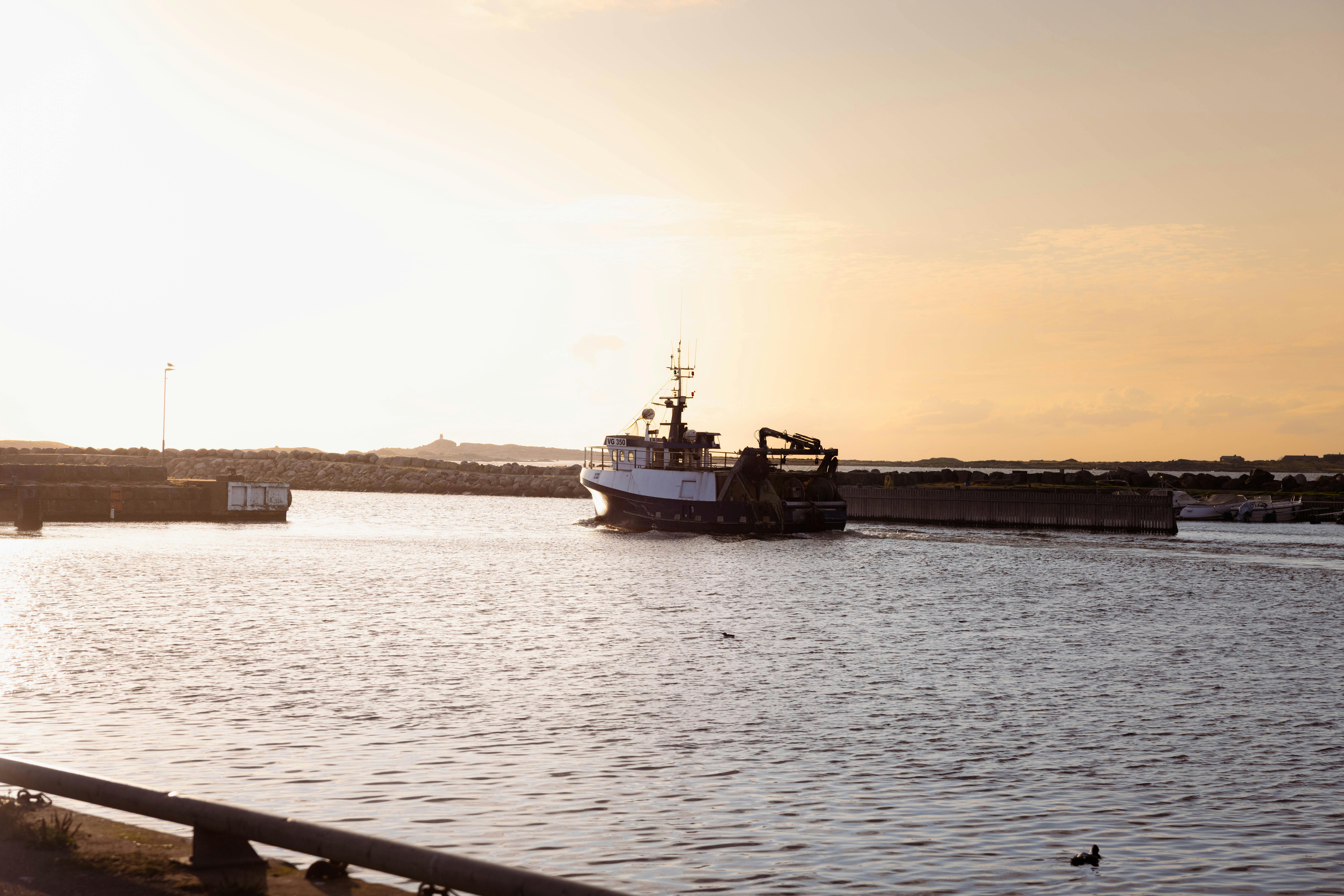 Fischerboot verlässt den Hafen im Sonnenuntergang.