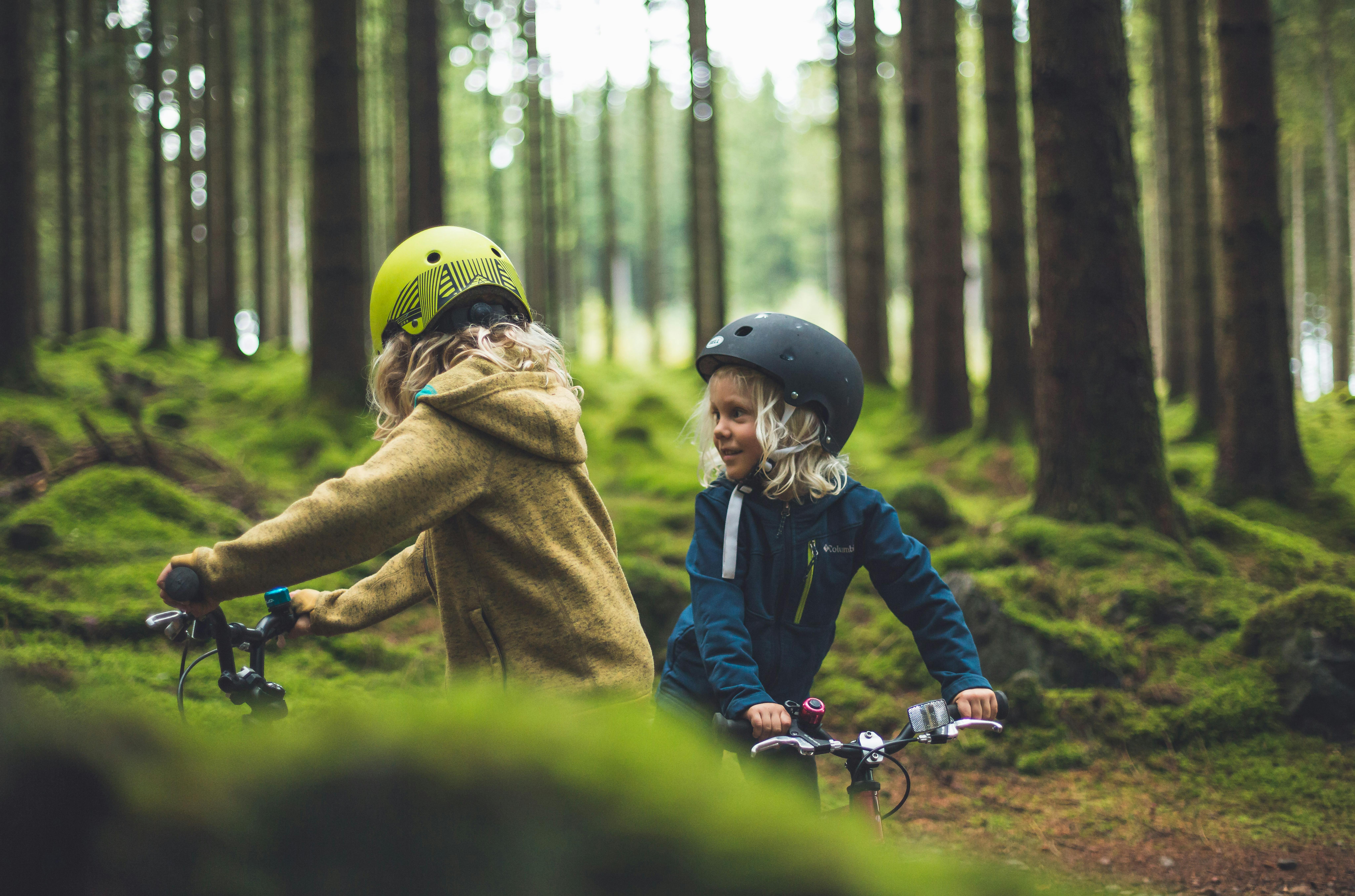 Zwei Kinder auf Rädern im Wald.