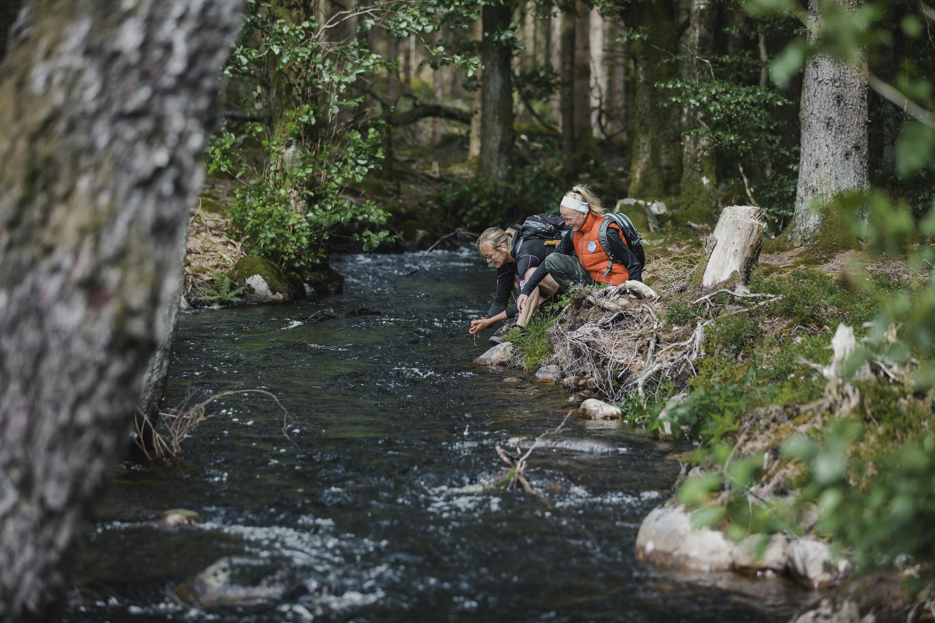 Mutter und Tochter am Fluss im Wald.