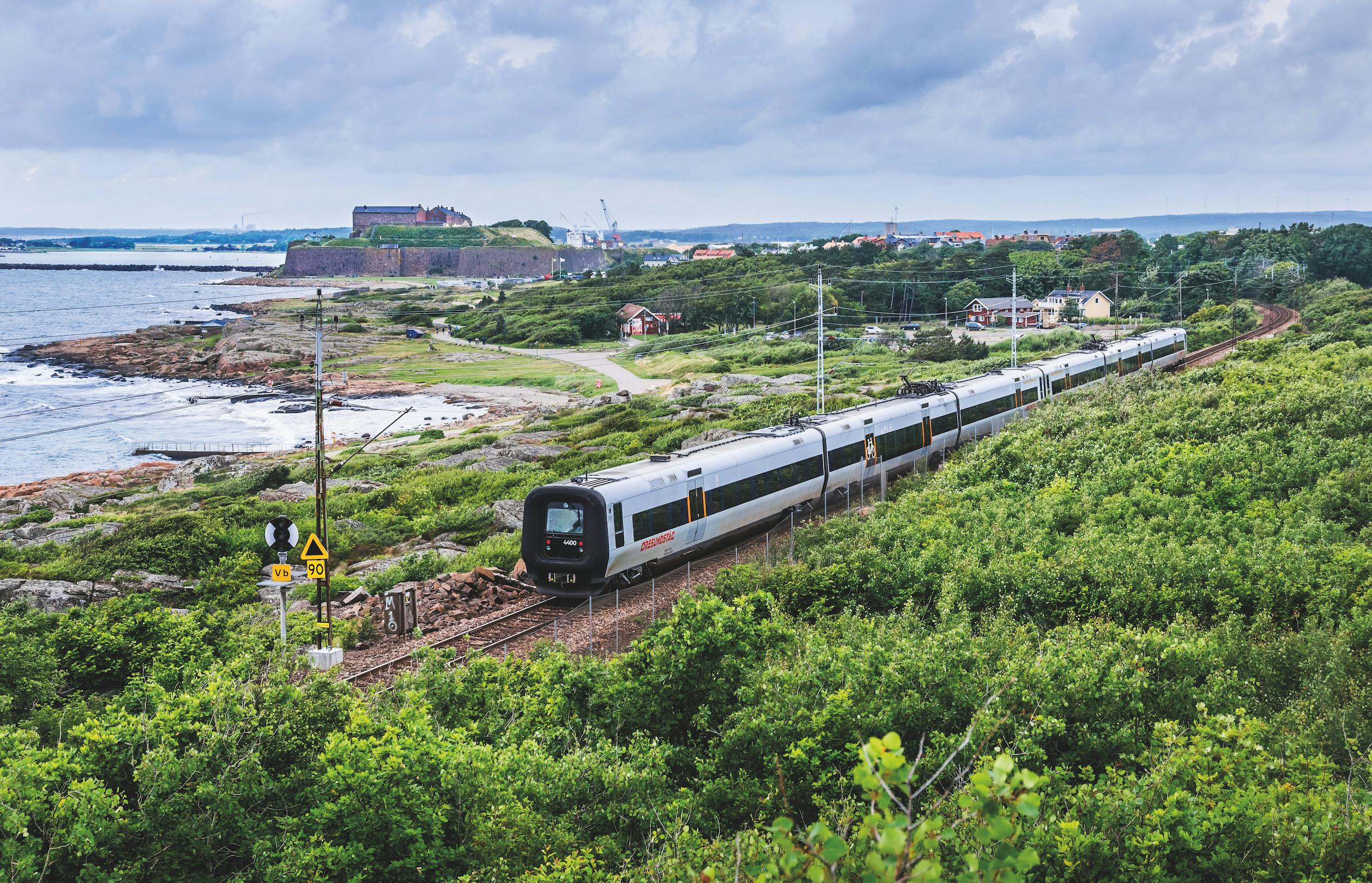 Tåg som kör i Varberg utmed havet