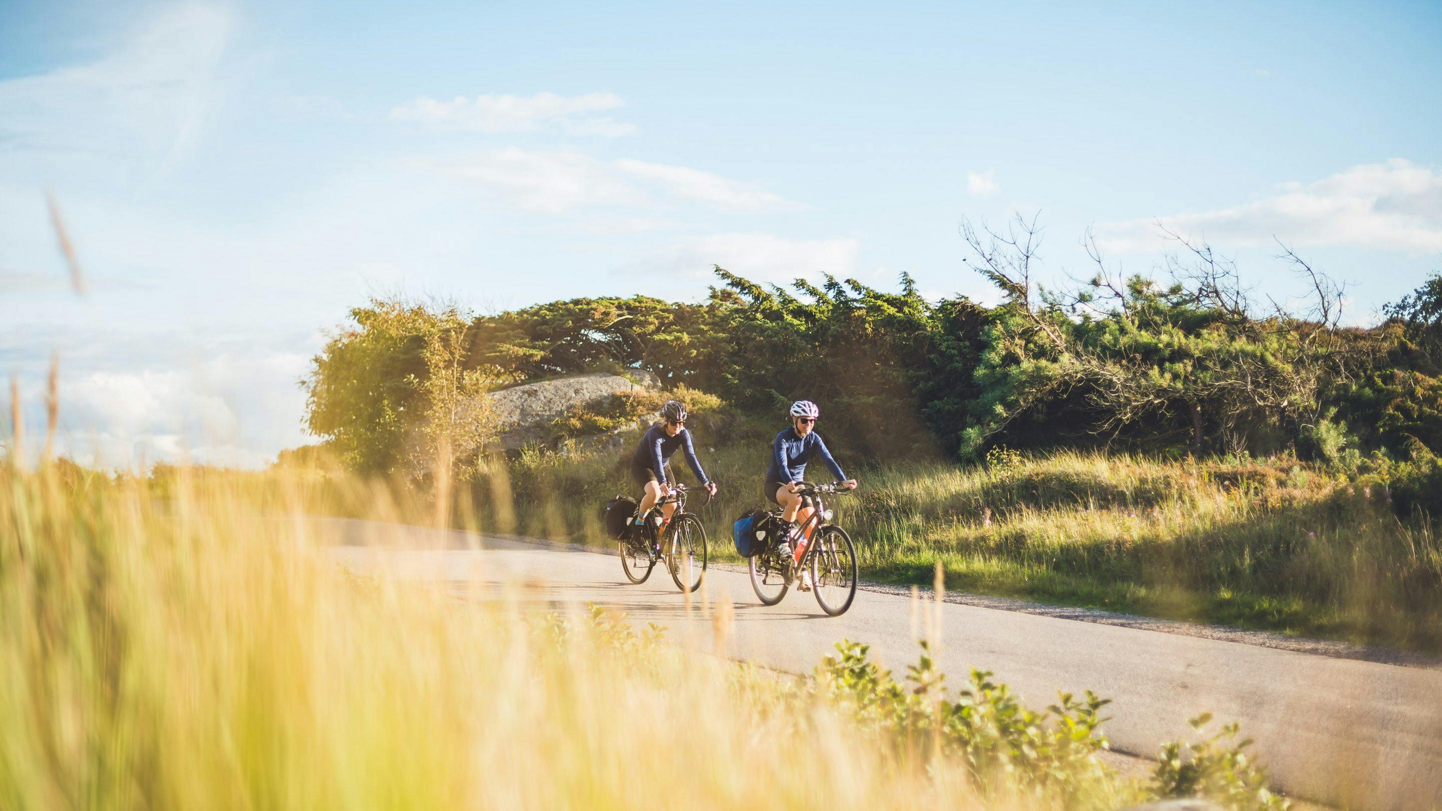 Två personer cyklar i solen.