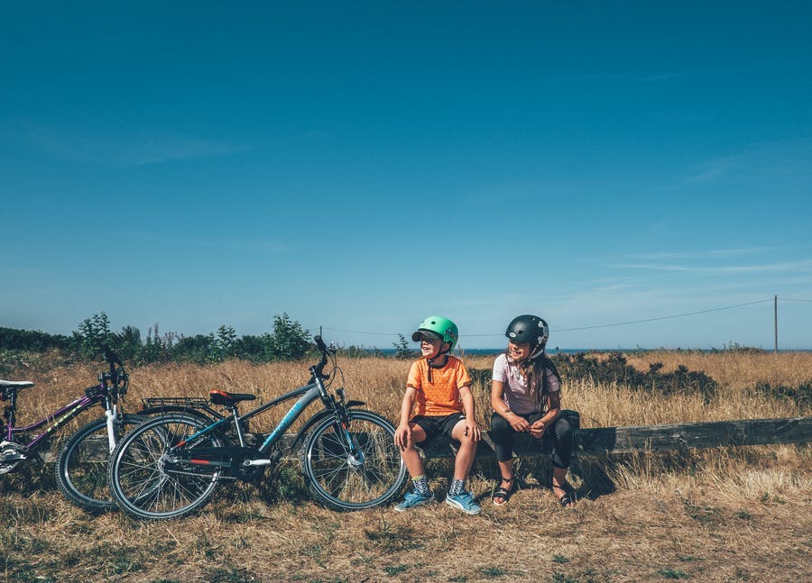 Två barn sitter och vilar med cyklarna bredvid.