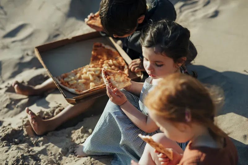 Barn äter pizza på stranden i Halland.