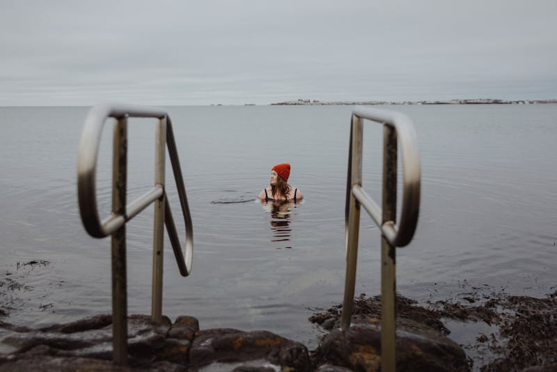 Kvinna i röd mössa kallbadar i Varberg, Halland.