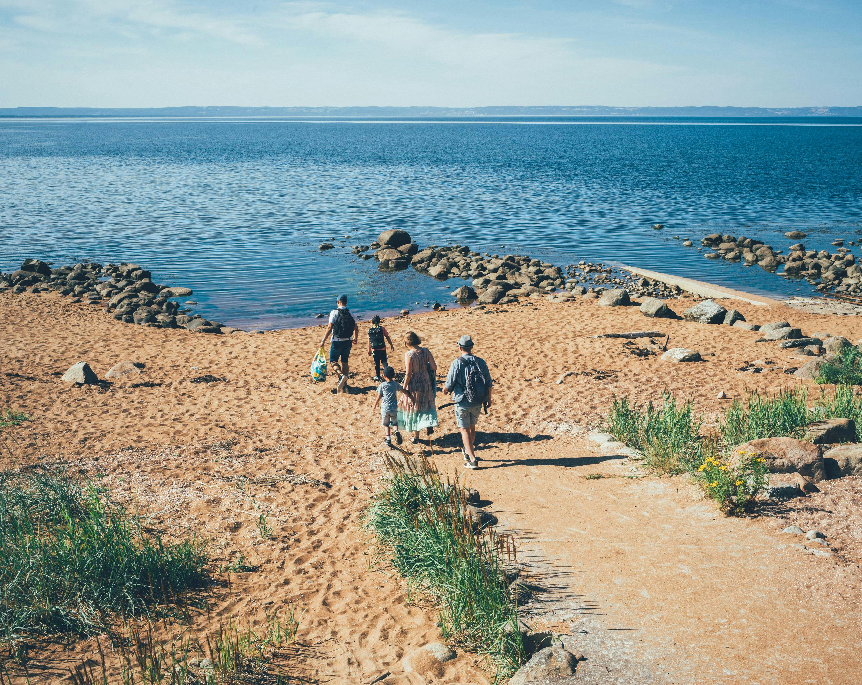 Tre vuxna och två barn är på väg ner till stranden.