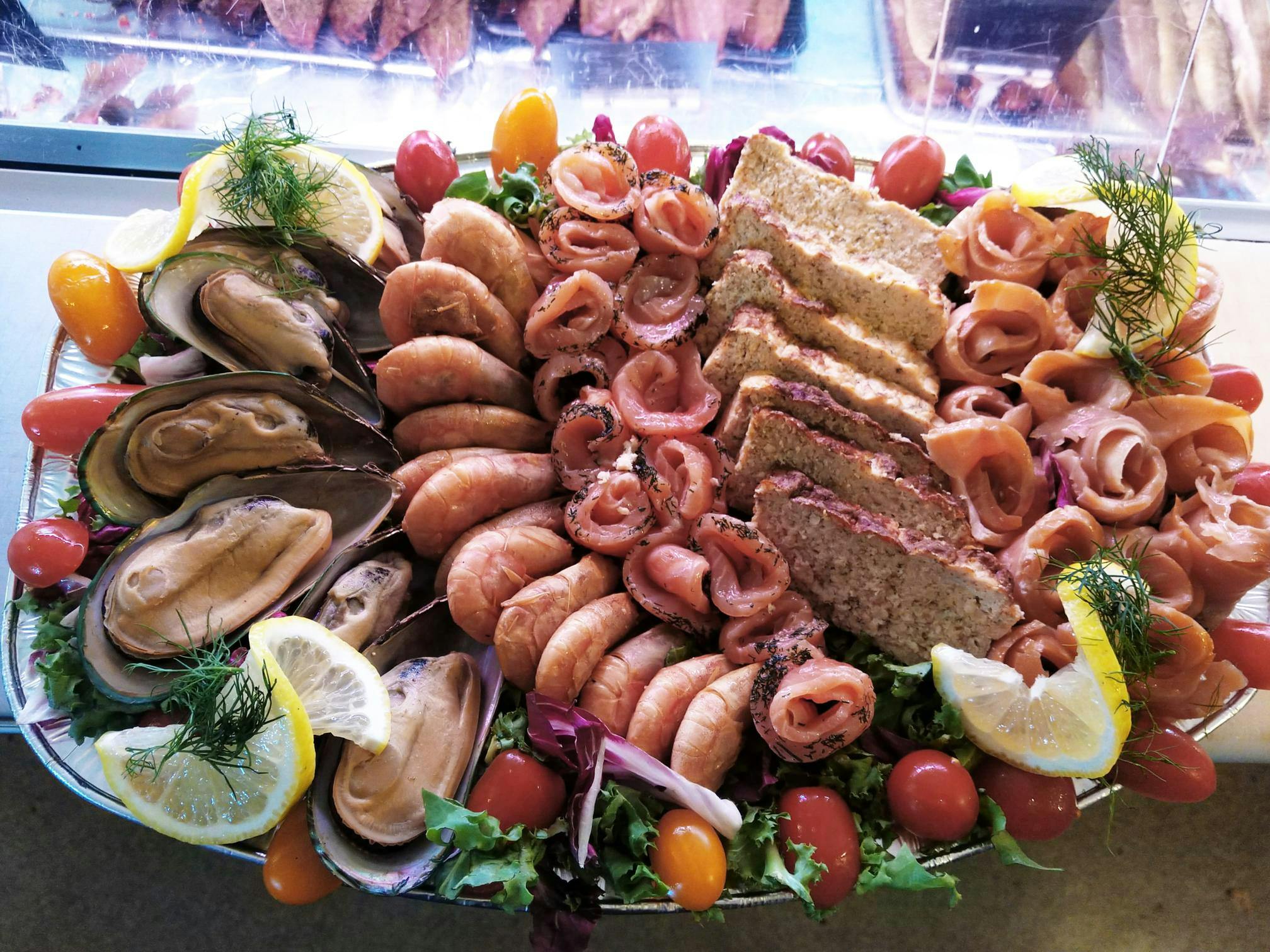 Närbild på en fisk och skaldjursplanka med räkor, ihoprullade lax bitar, musslor, fiskpaté, citronskivor o.s.v