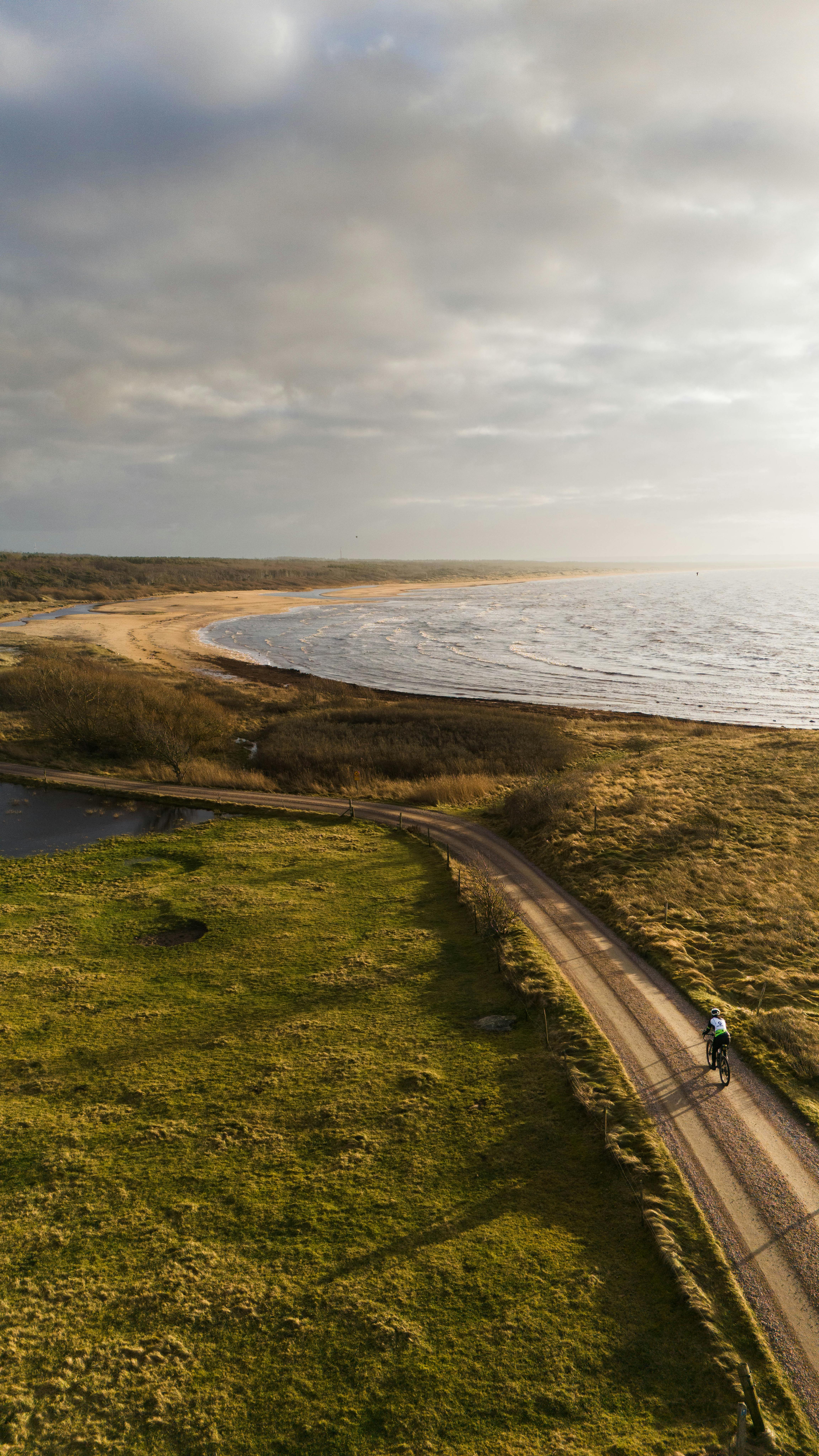 Radweg entlang der Küste mit Strand und Sonnenuntergang.