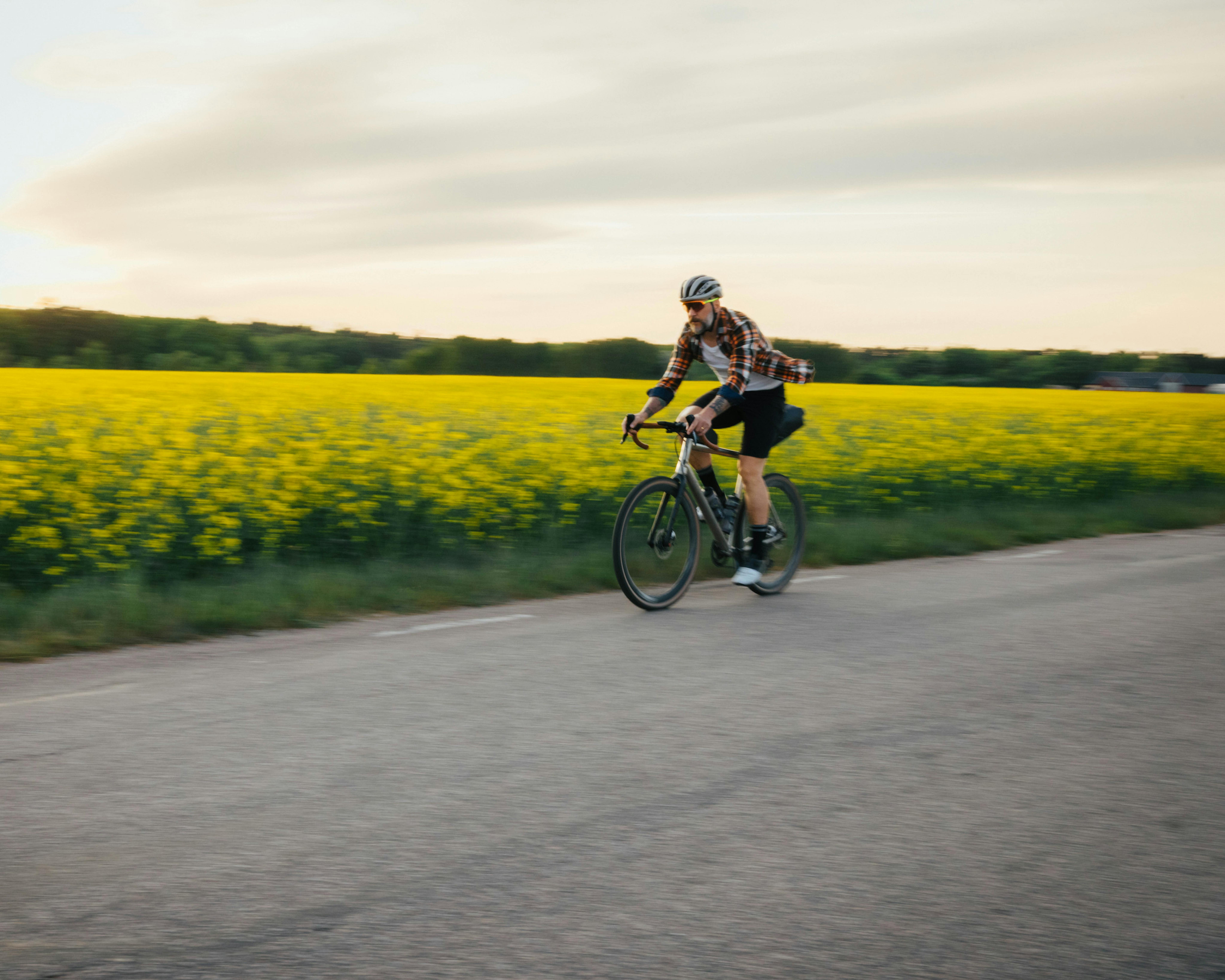 Mann mit Rennrad vor gelber Blumenwiese im Frühling.
