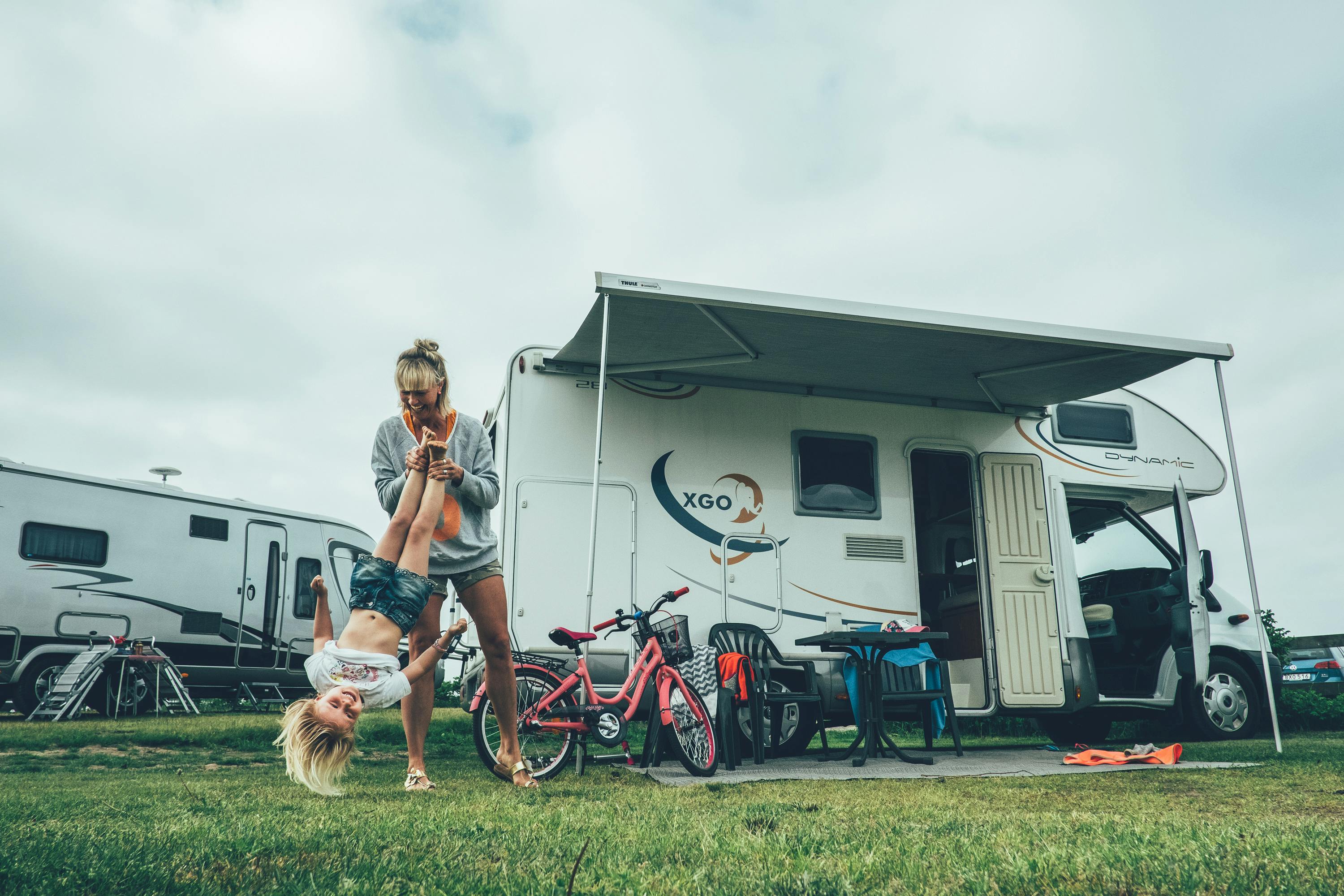 Mutter spielt mit Kind am Campingplatz vor dem Wohnmobil.