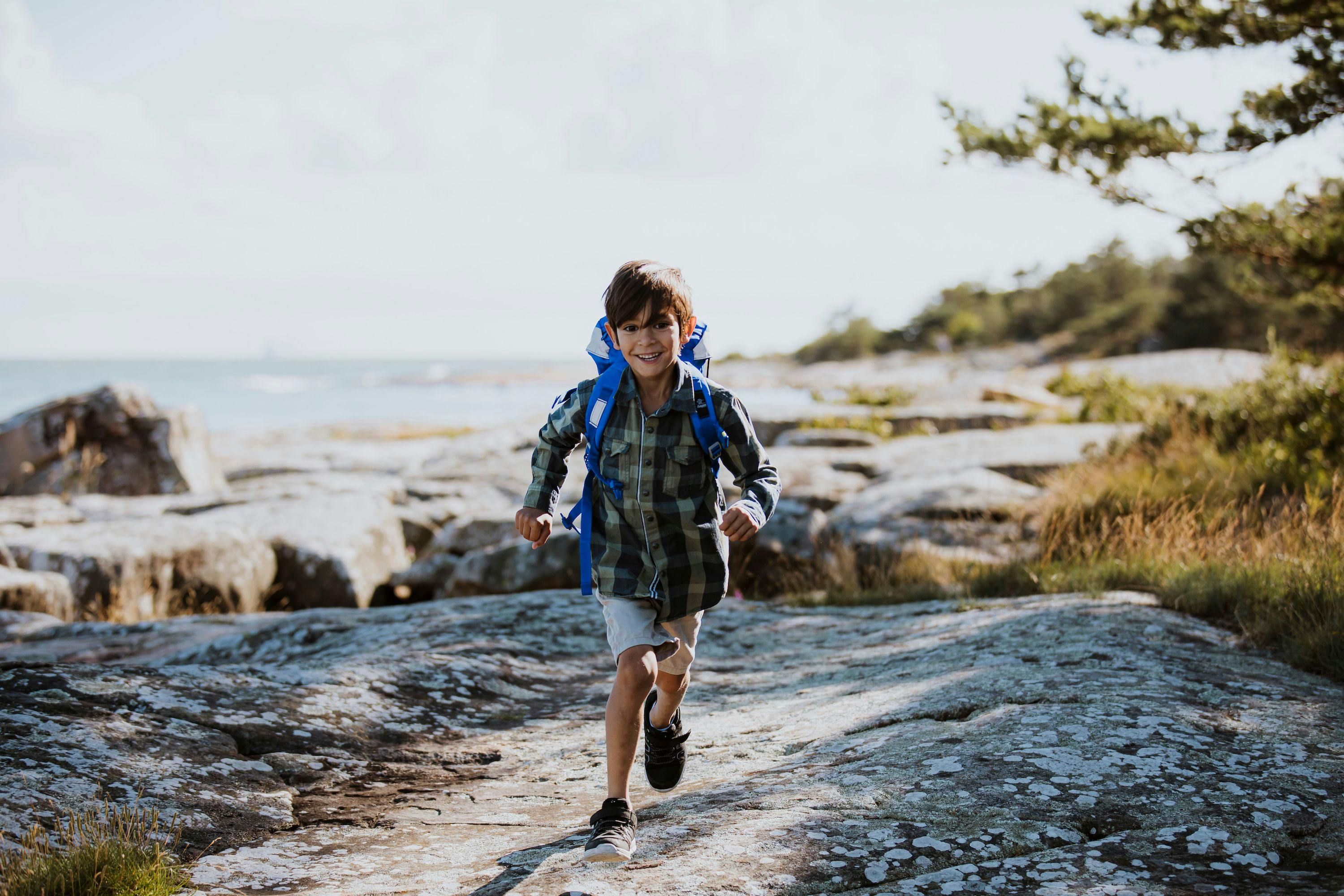 Ett barn springer på klipporna vid havet.