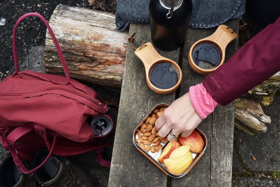 Kaffet är upphällda i koppar och matlådan är framdukad ute i naturen.