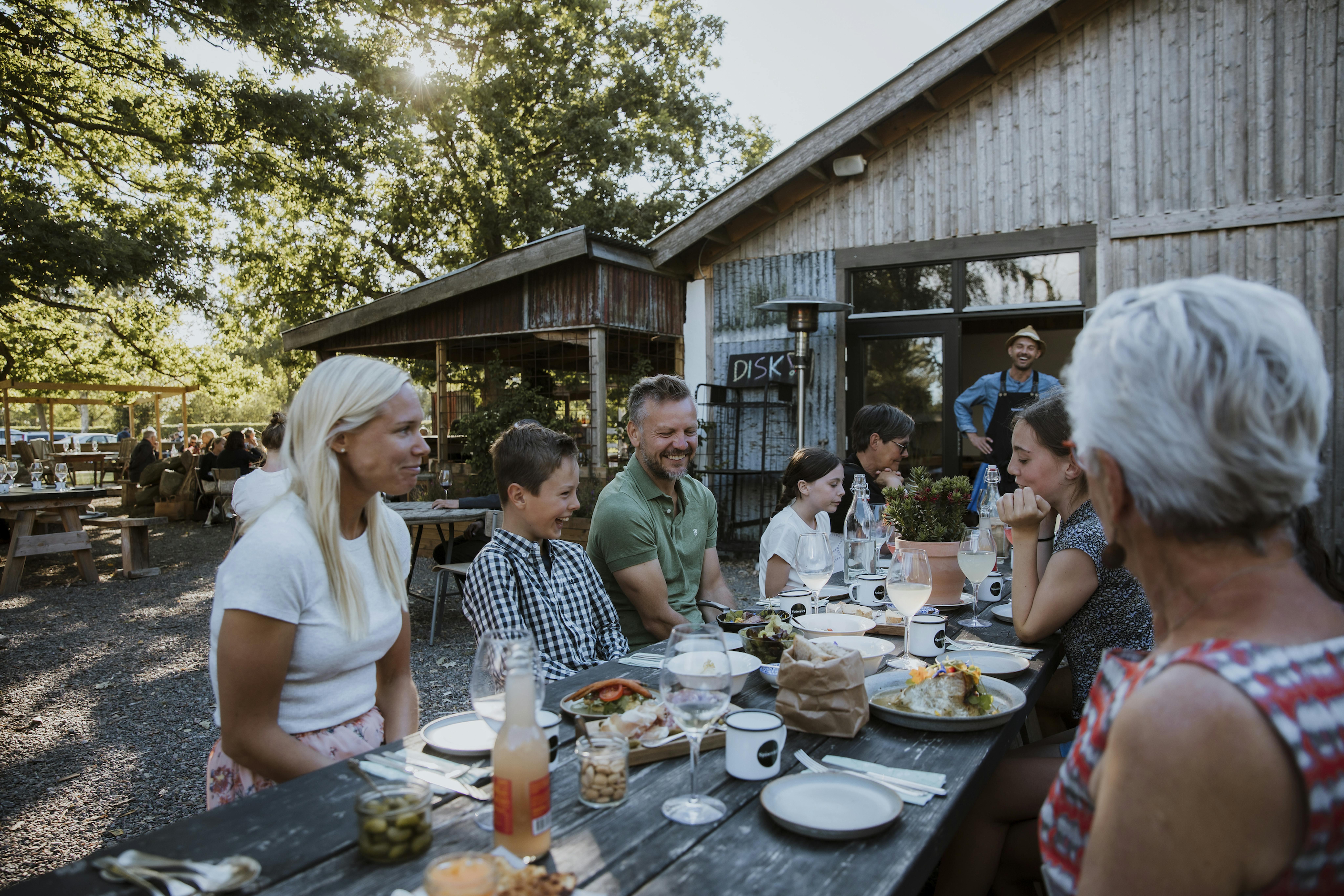 Familie isst draußen am Holztisch bei Spiseriet in Varberg.