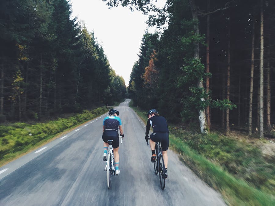Två personer cyklar på en tom landsväg.