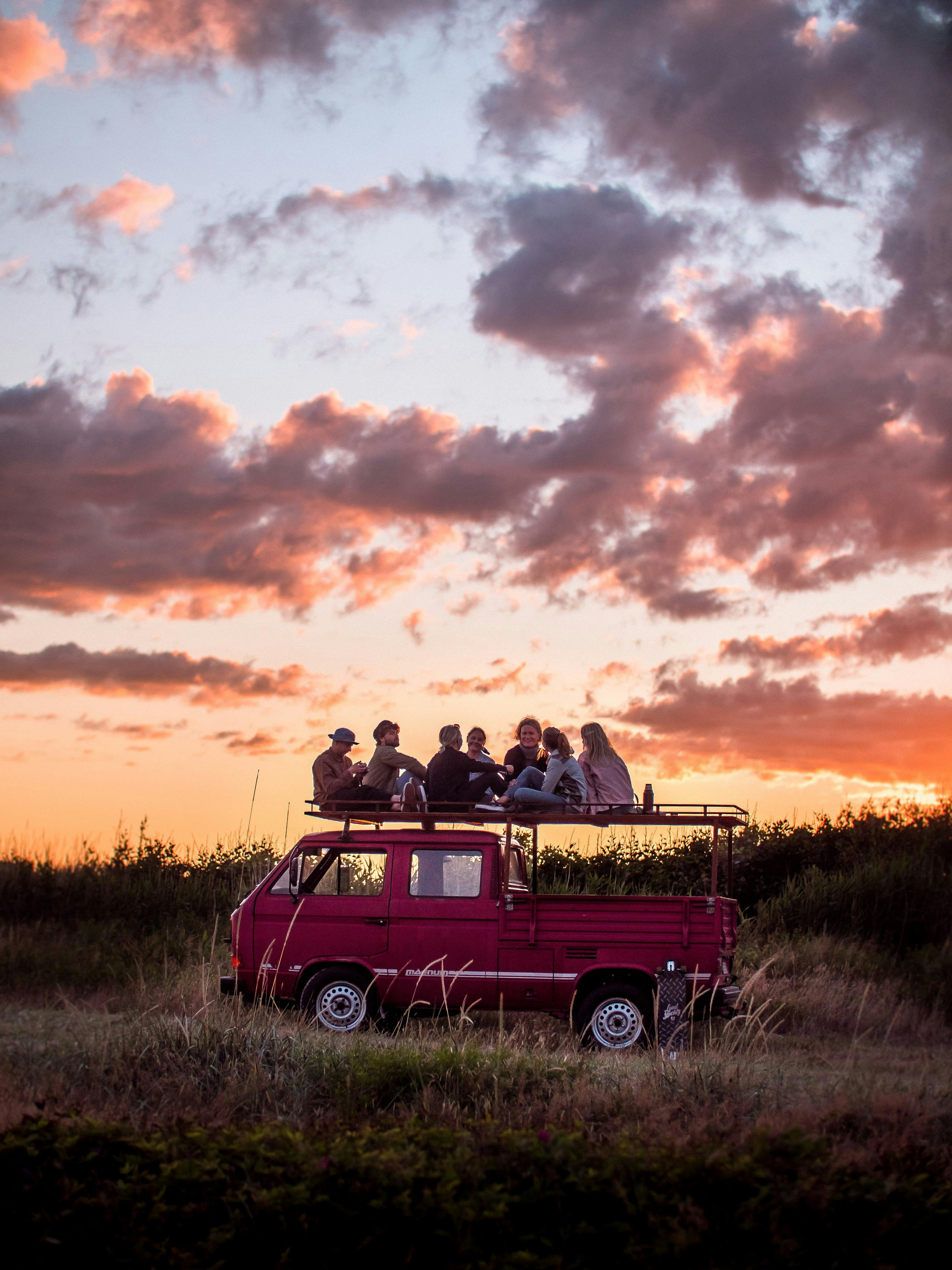 Ett kompisgäng sitter på ett bilflak och njuter.