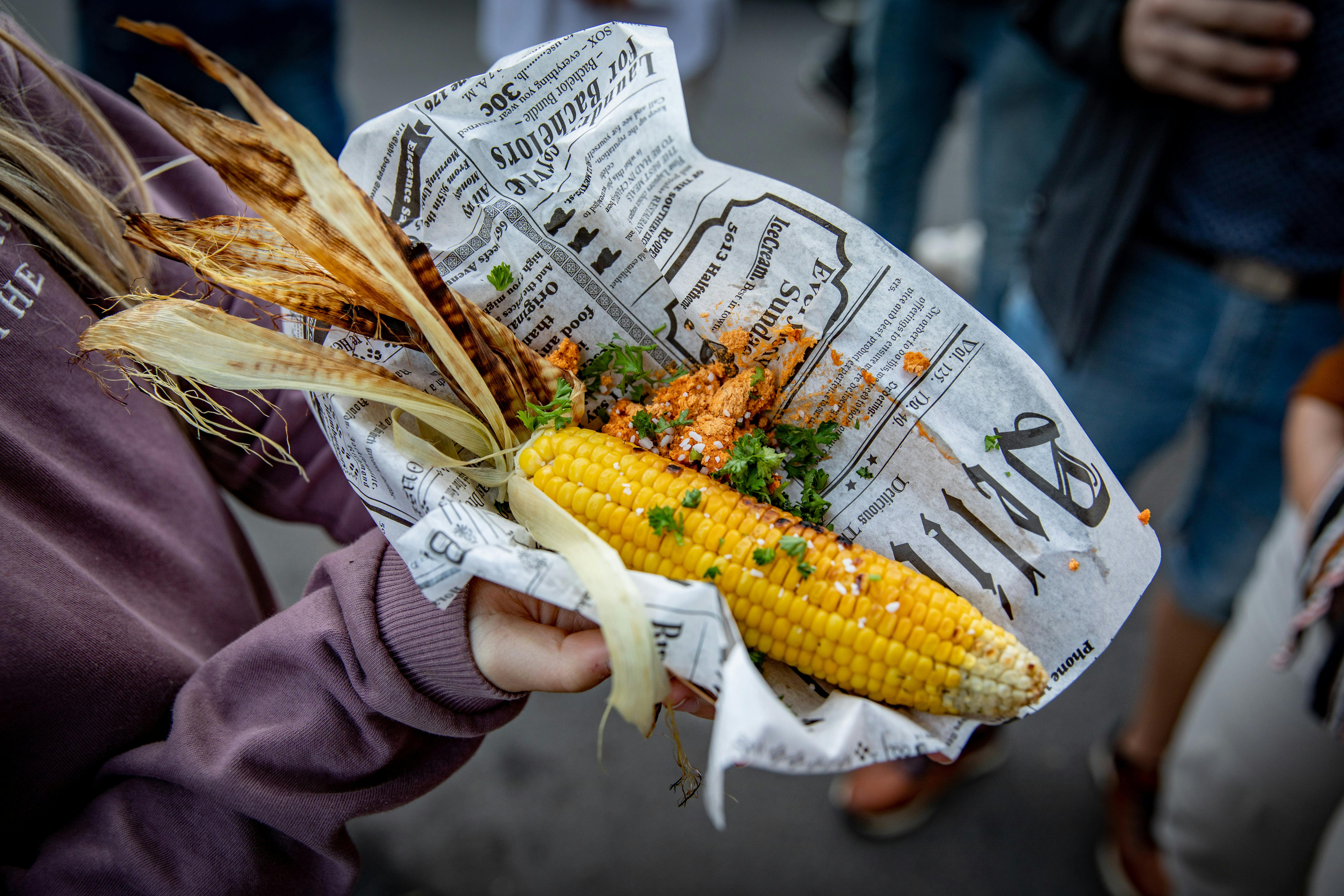 Person hält Maiskolben zum Verzehr