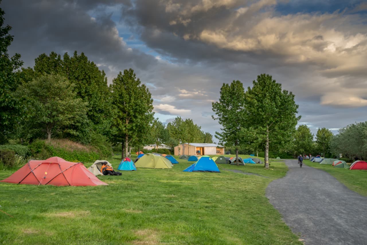 colourful tents next to a gravel path surrounded by trees