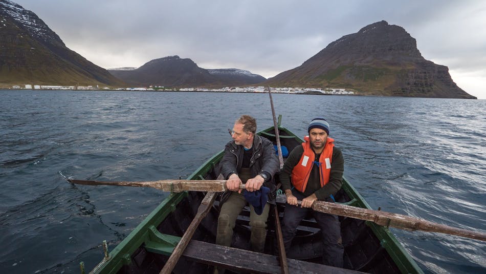 Two men rowing a boat toward Bolungarvík, Iceland 