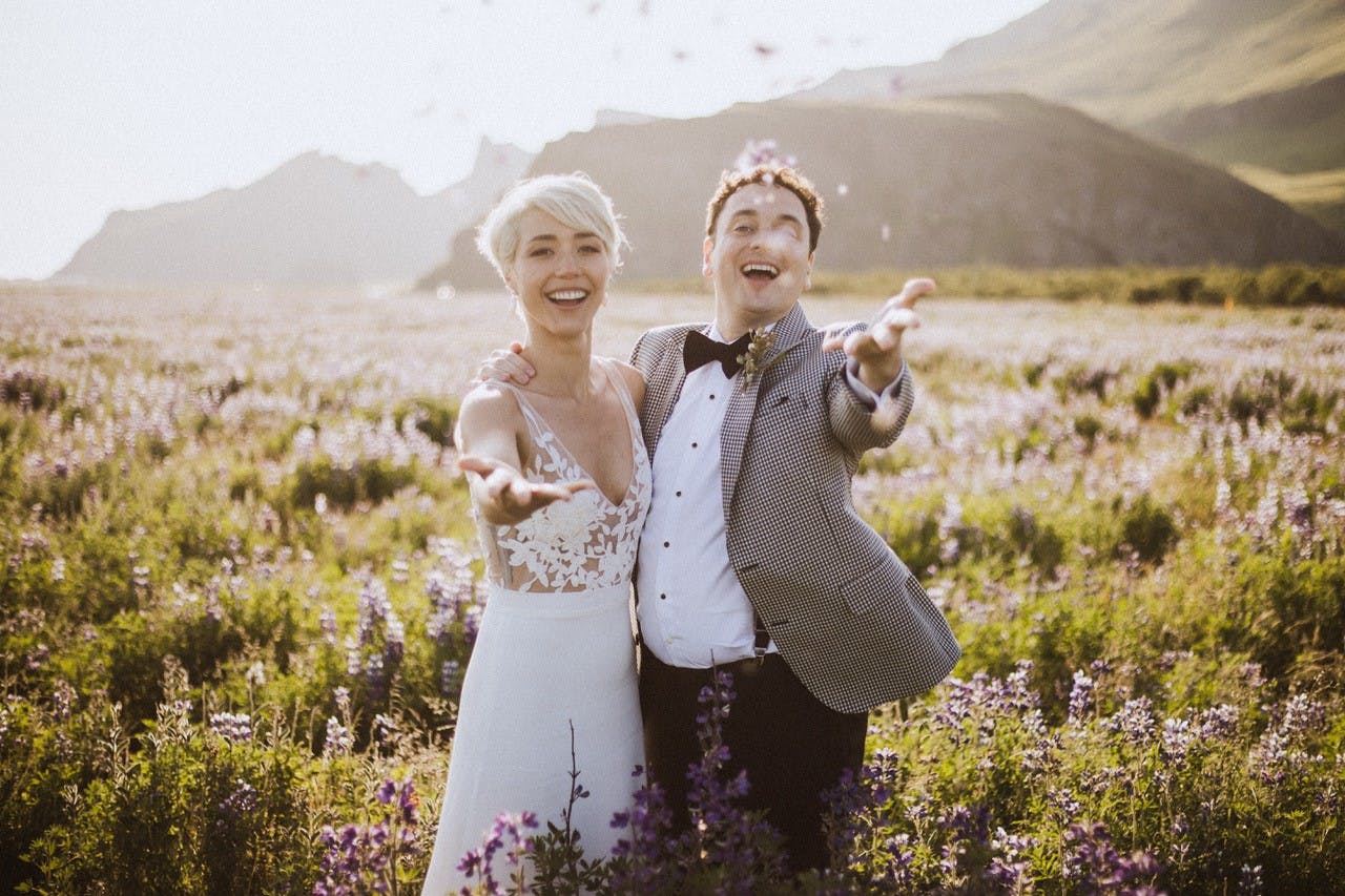 A couple in wedding attire out in nature with lupine flowers in background