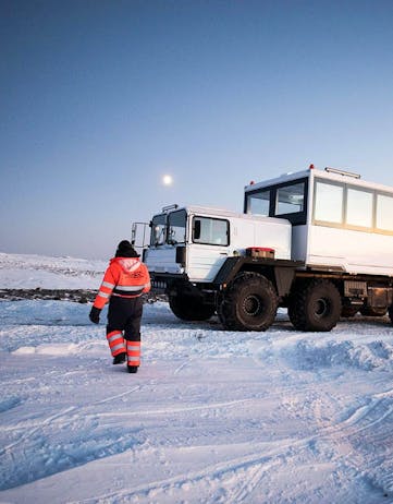 A man walking by a big truck on a glacier